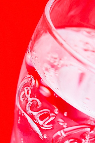 A glass of mineral water with a red background.