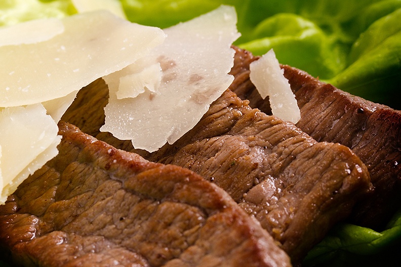 Some small pieces of baked beef (1 minute) on a piece of lettuce with some Parmesan cheese flakes.