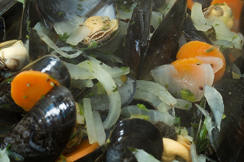 Mussels cooked in white wine with herbs and vegetables, served with a salad and french fries