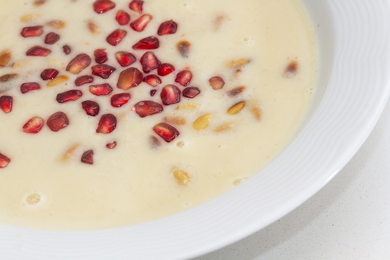 Home made garlic soup with pine nuts and pomegranate seeds
