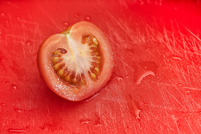 Tomato an a red (used) cutting board