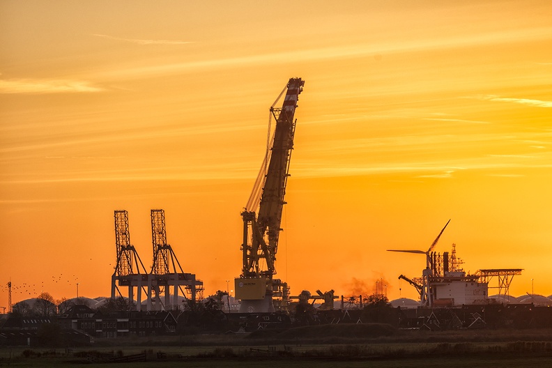 Big cranes in an orange colored sky at sunset