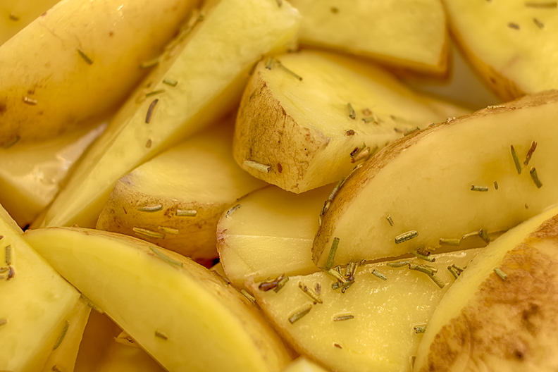 Potato parts with dried rosemary and olive oil, ready for the oven
